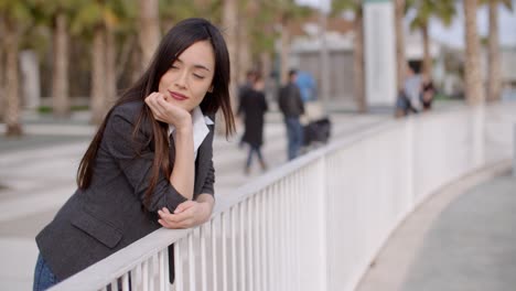 young thoughtful woman leaning on a railing