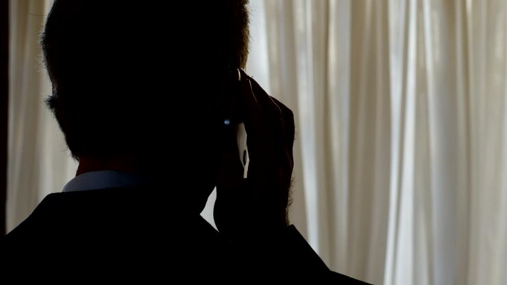 Intercettazione telefonica: uomo che parla al telefono al crepuscolo