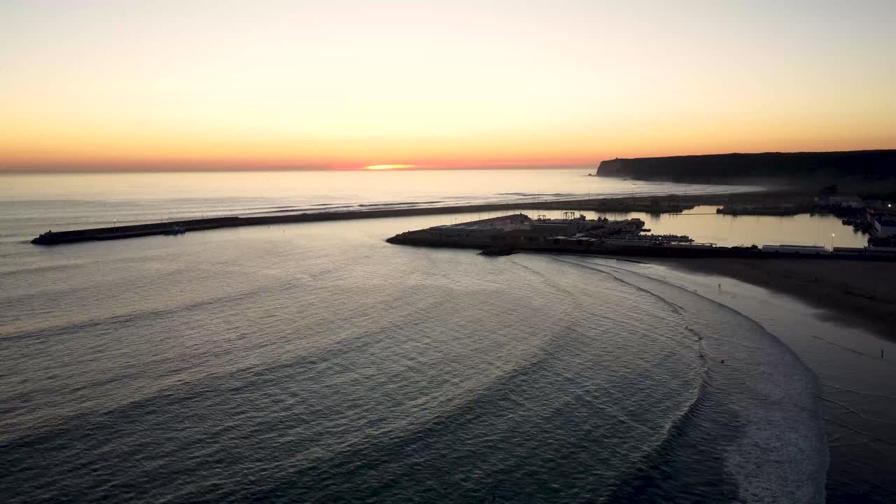 Lenta inquadratura introduttiva della silhouette di un porto al tramonto.