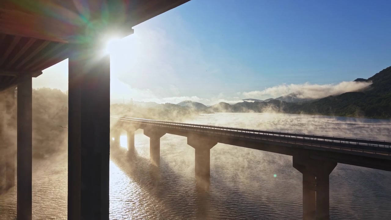 橋越しの日の出、水面から立ち上る霧と柱の間から差し込む太陽の光