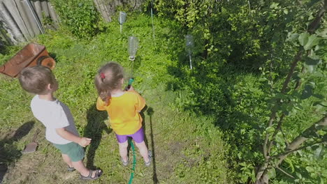 Children-watering-plants-in-the-yard-of-country-house