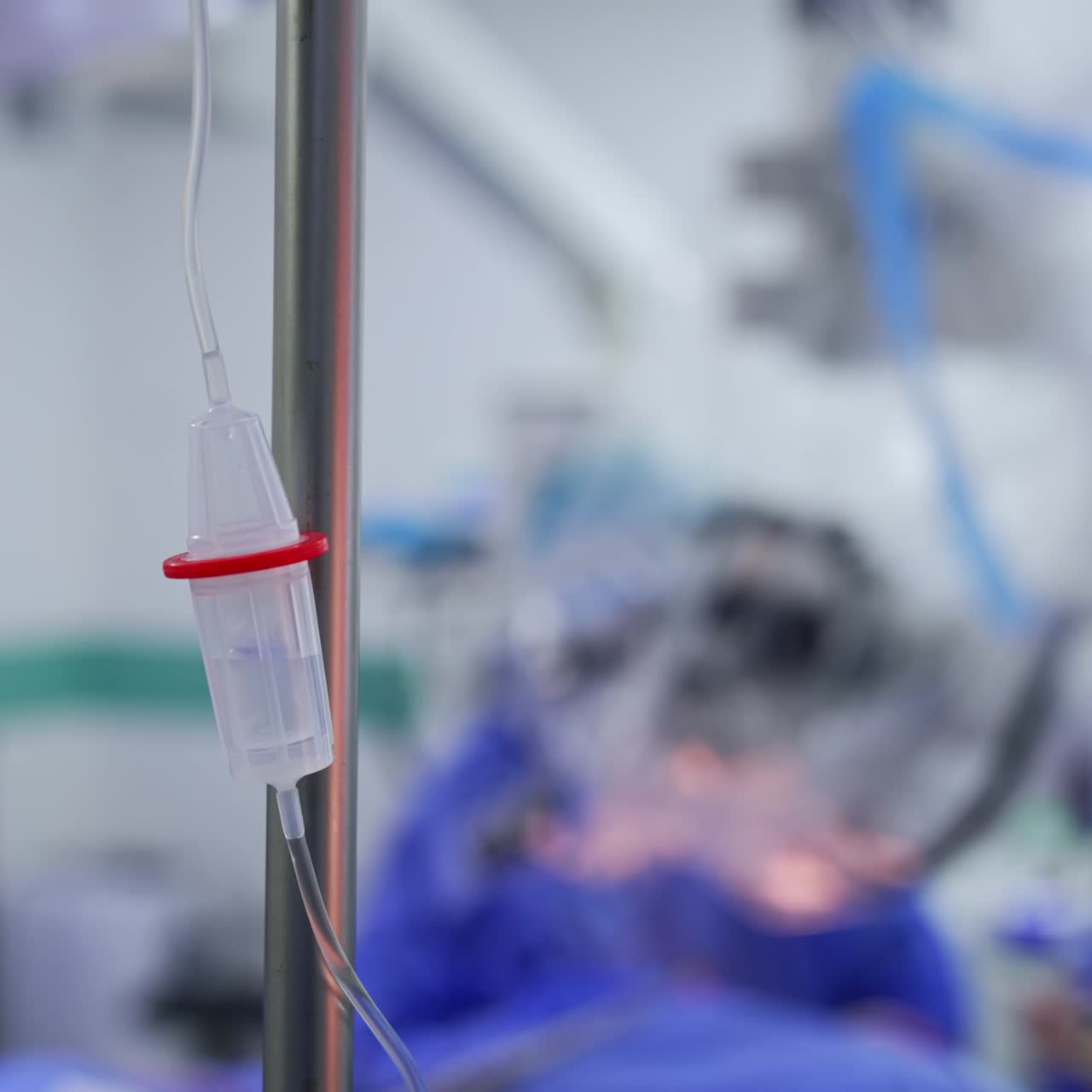 Dropper for measuring out drops of medicine or other liquids hanging in the surgical room. Group of medics working at backdrop in blur