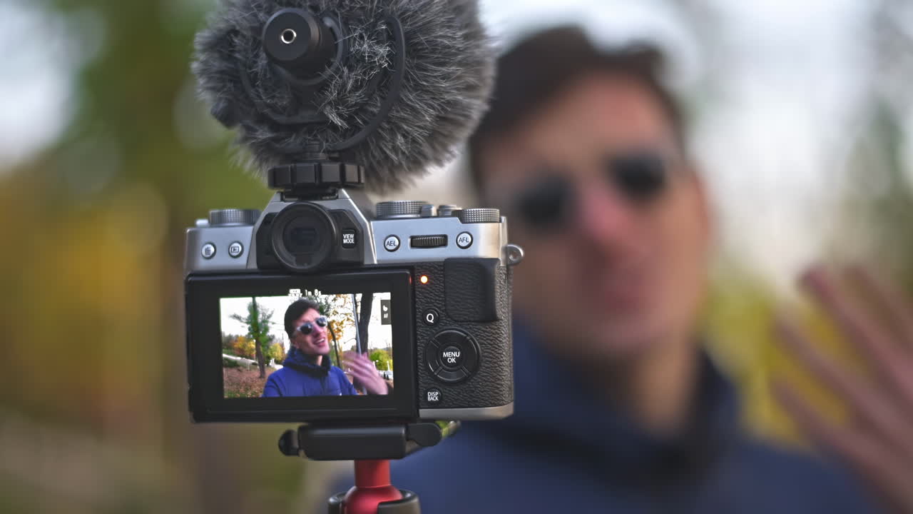 Young man vlogger speaking motivationally to the camera in autumn park