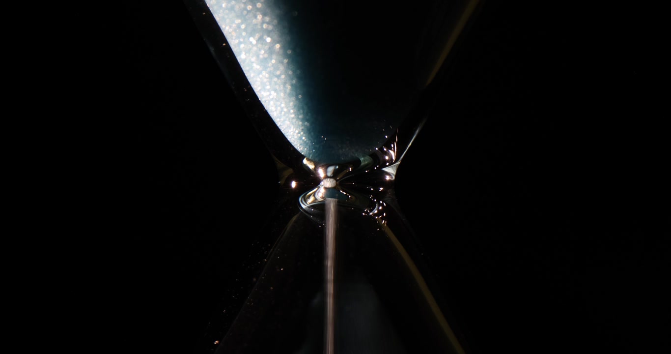White shiny sand pours down inside vintage time measurement tool