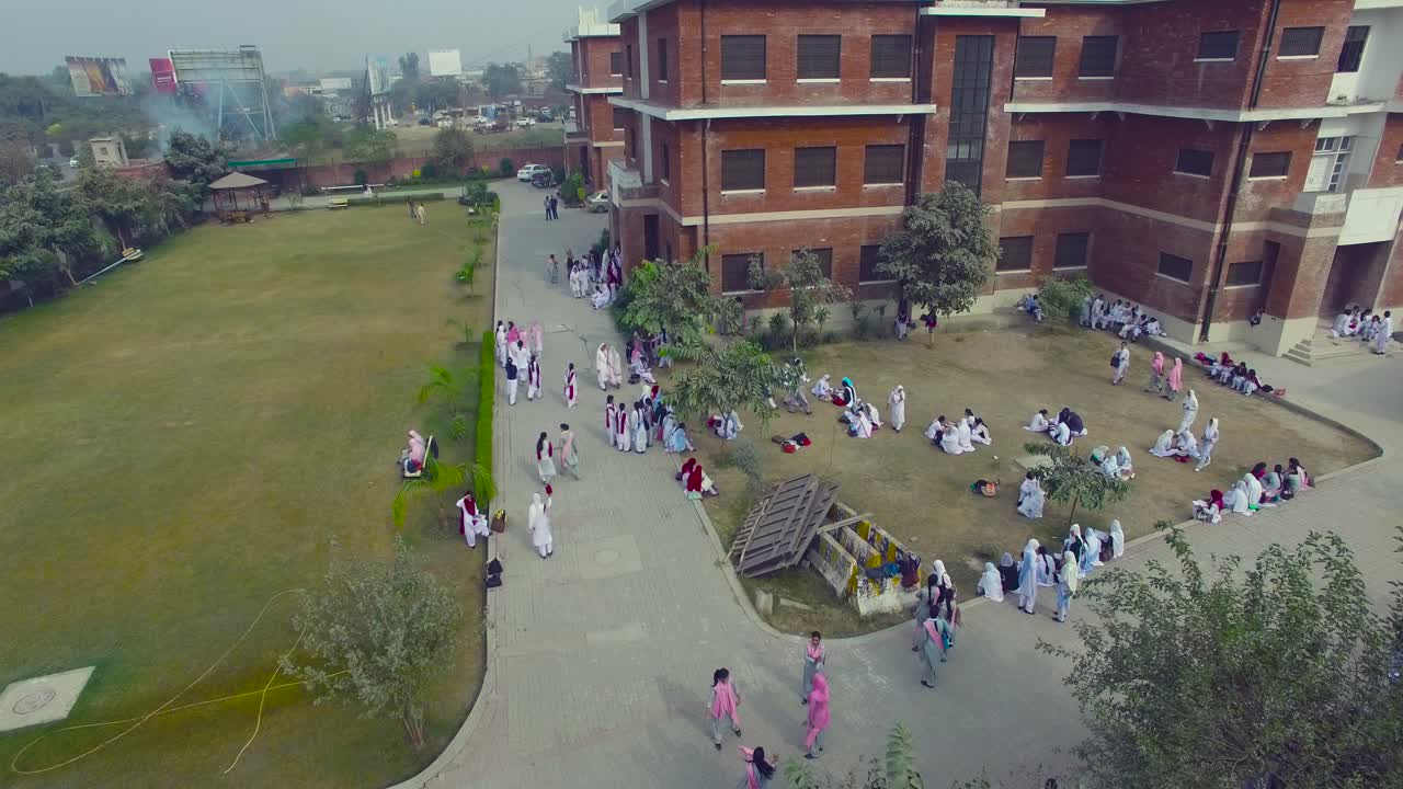 Bombay, India. Pemandangan udara kampus khusus putri. Mahasiswi berada di area kampus. Mahasiswa/i berjalan, duduk, dan bersenang-senang di kampus.