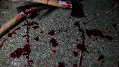 camera moves over blood spatters on the ground and finds a pile of bloody murder weapons, shears an axe and a hammer