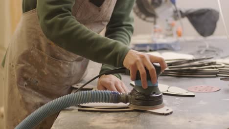 a carpenter grinds a piece of wood, plywood product made on a cnc laser machine with a grinder