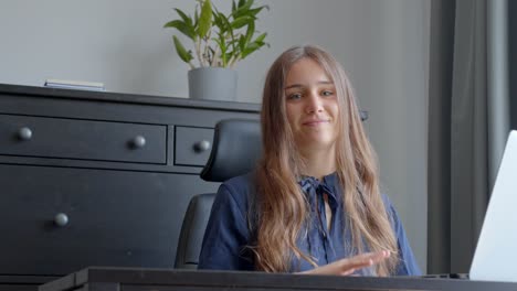 young woman poses elegantly opening arms while working with laptop at office