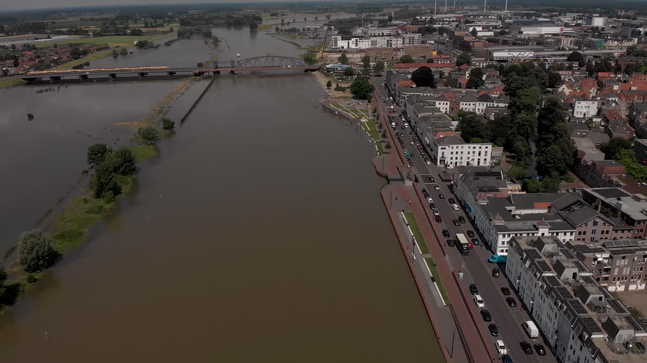 descenso aéreo y panorámica lateral que muestra el paisaje urbano de zutphen, los países bajos, con el tráfico que pasa por el bulevar durante los altos niveles de agua del río ijssel llenando las llanuras aluviales