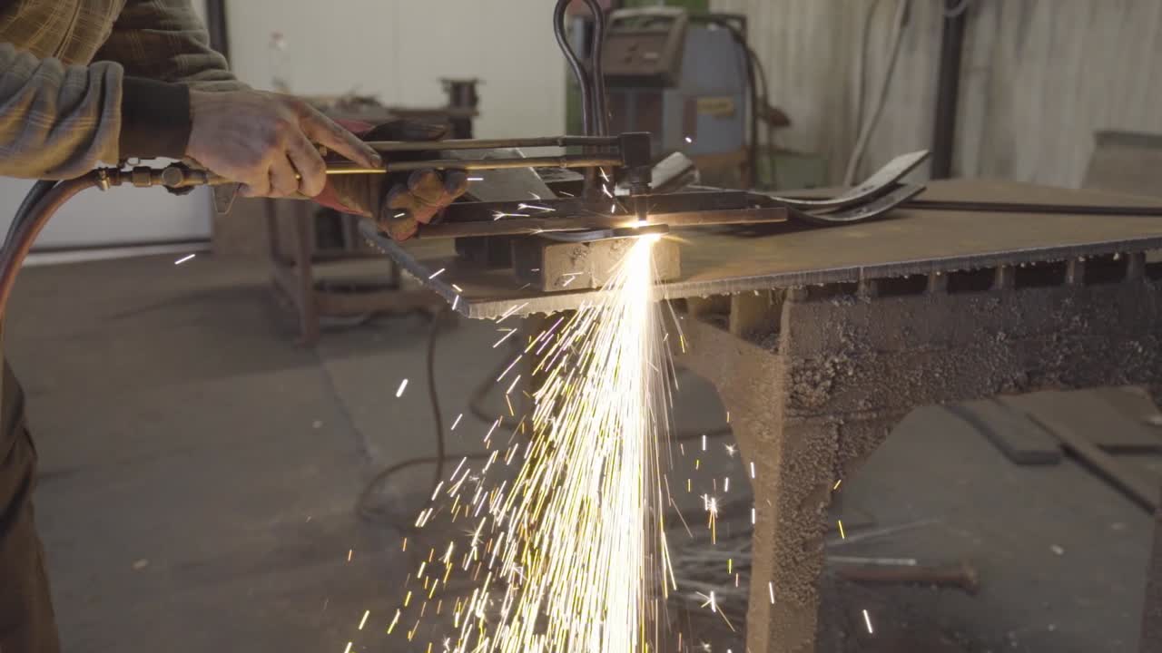 Cutting a thick steel plate with handheld plasma cutter. Amazing spark shower in the workshop