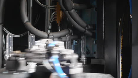 a close-up shot of how pet preforms are moving into a moulding machine, where they are blown into a plastic bottle