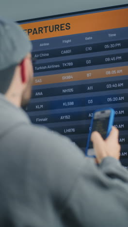 person checking flight departure at airport terminal