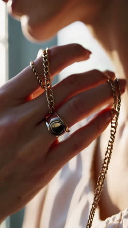 close-up of a hand holding a gold chain and ring