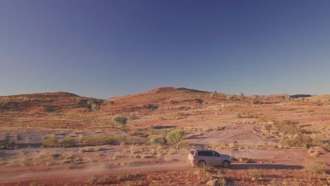 drone aéreo rastreando un camión 4wd por un camino de grava en el desierto australiano