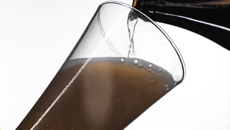 close up background of pouring beer with bubbles and foam in glass low angle side view slow motion