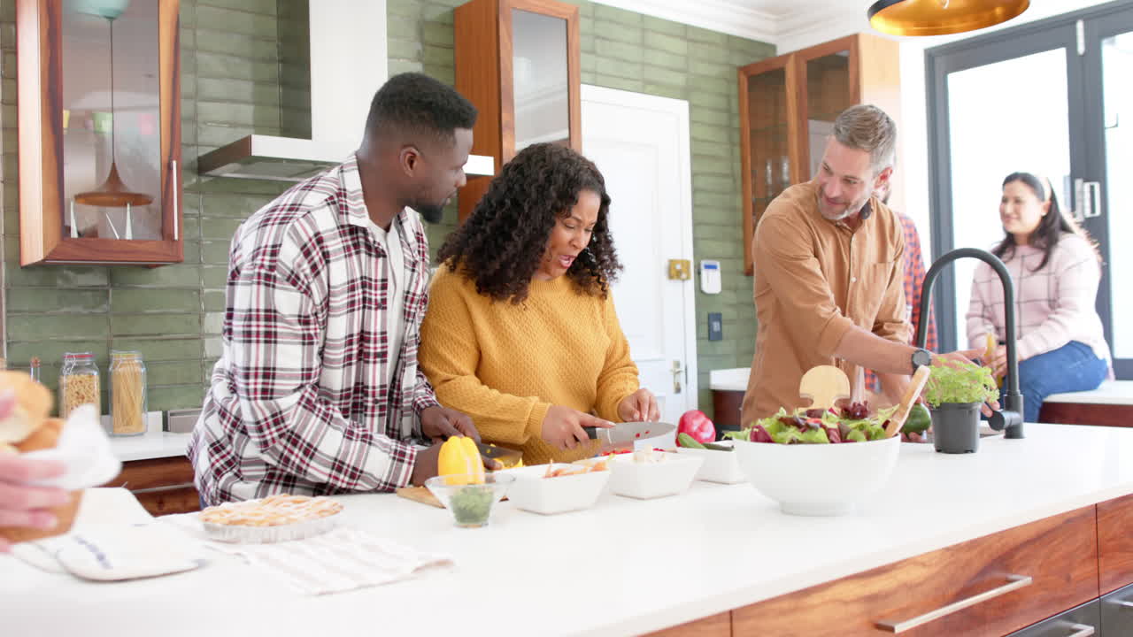Happy diverse male and female friends preparing food together in kitchen