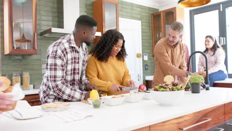 happy diverse male and female friends preparing food together in kitchen