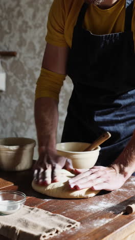 close-up of hands kneading dough on a wooden table