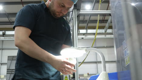 trabajador de la fábrica comprobando las tapas de los frascos a la luz en el almacén