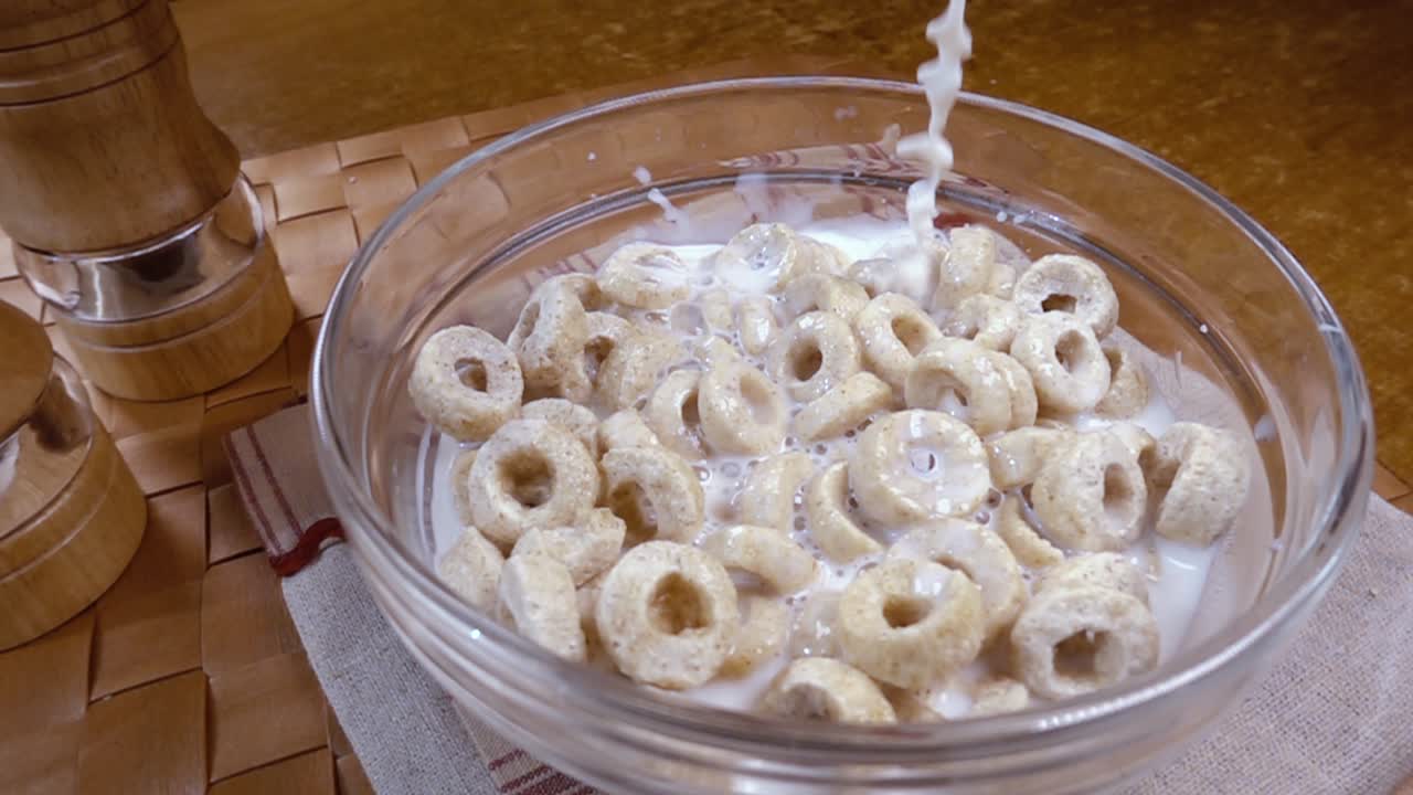 Fiocchi d'avena croccanti in una ciotola per una deliziosa colazione mattutina con latte. Slow motion con ripresa rotatoria.