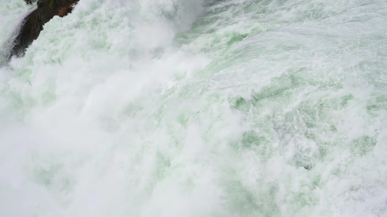 Rushing waterfall in slow motion with foam and water swirling around
