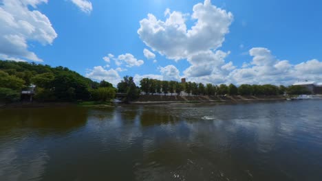 a scenic river landscape under a bright blue sky with white clouds