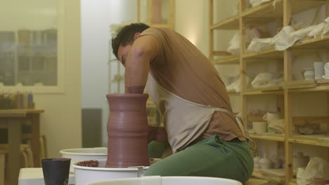 Joven-Artesano-Haciendo-Escultura-De-Vasija-Hecha-A-Mano-En-Torno-De-Alfarería-De-Taller