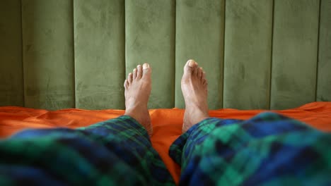 bare feet in plaid pajamas on an orange bed