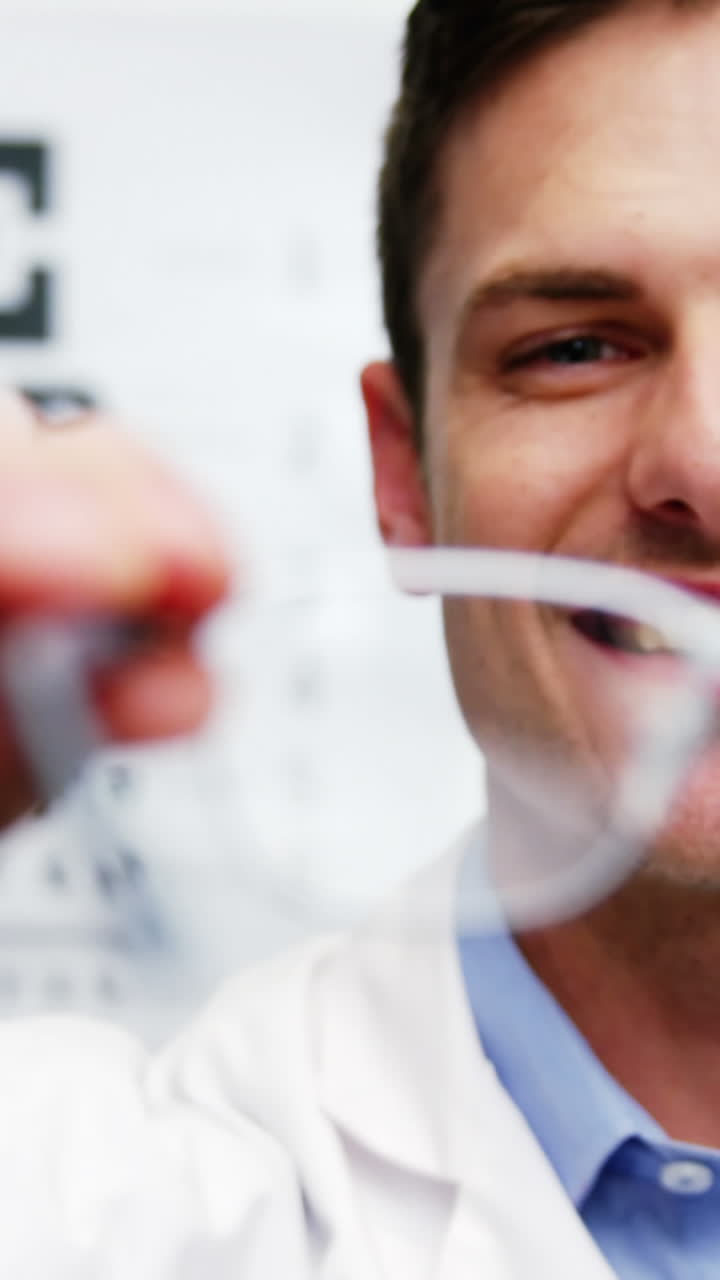 un optometrista sorridente che tiene gli occhiali