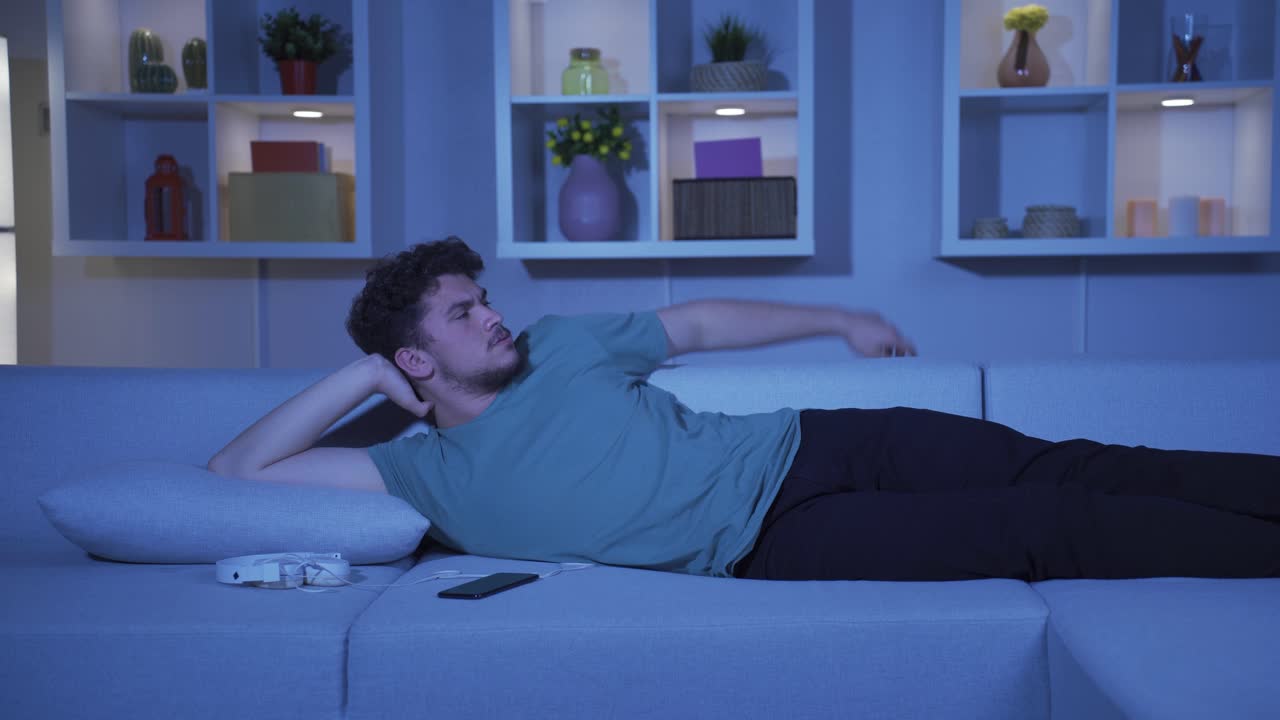 슬프고 불행한 남자가 밤에 집에서 음악을 듣고 있습니다.