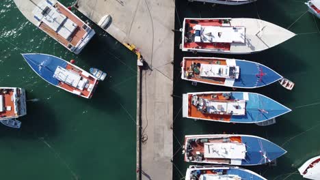 Aerial-flyover-jetty-with-docking-fishing-boats-during-sunny-day-at-port