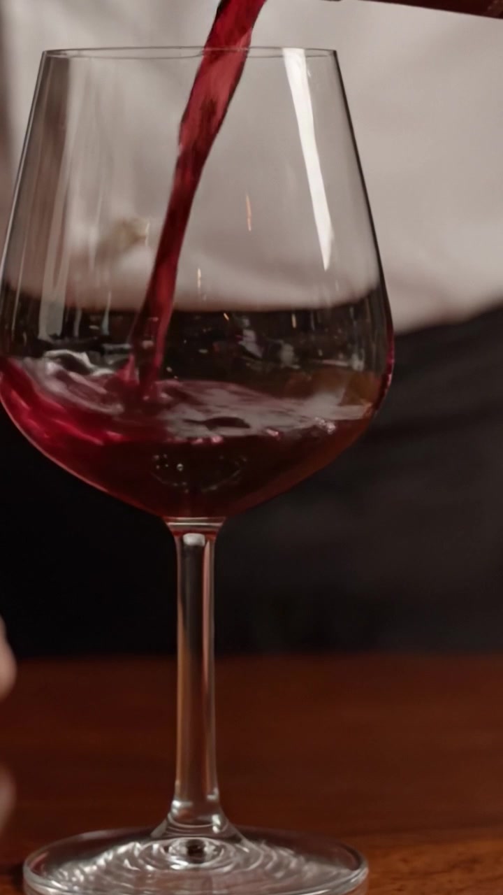 Uma Servida Elegante: Exibindo a Arte de Servir Vinho com uma Taça Delicada Sendo Preenchida com Rico Vinho Tinto, Capturando a Essência da Experiência de Alta Gastronomia.