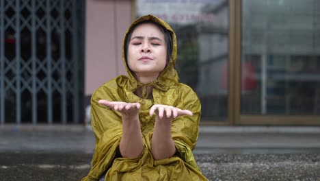 a young female freelance teacher boring squatting under roof waiting for rain to stop, being late for work, uncomfortable of getting wet in rainy day, reach out hands touching raindrops on palms,