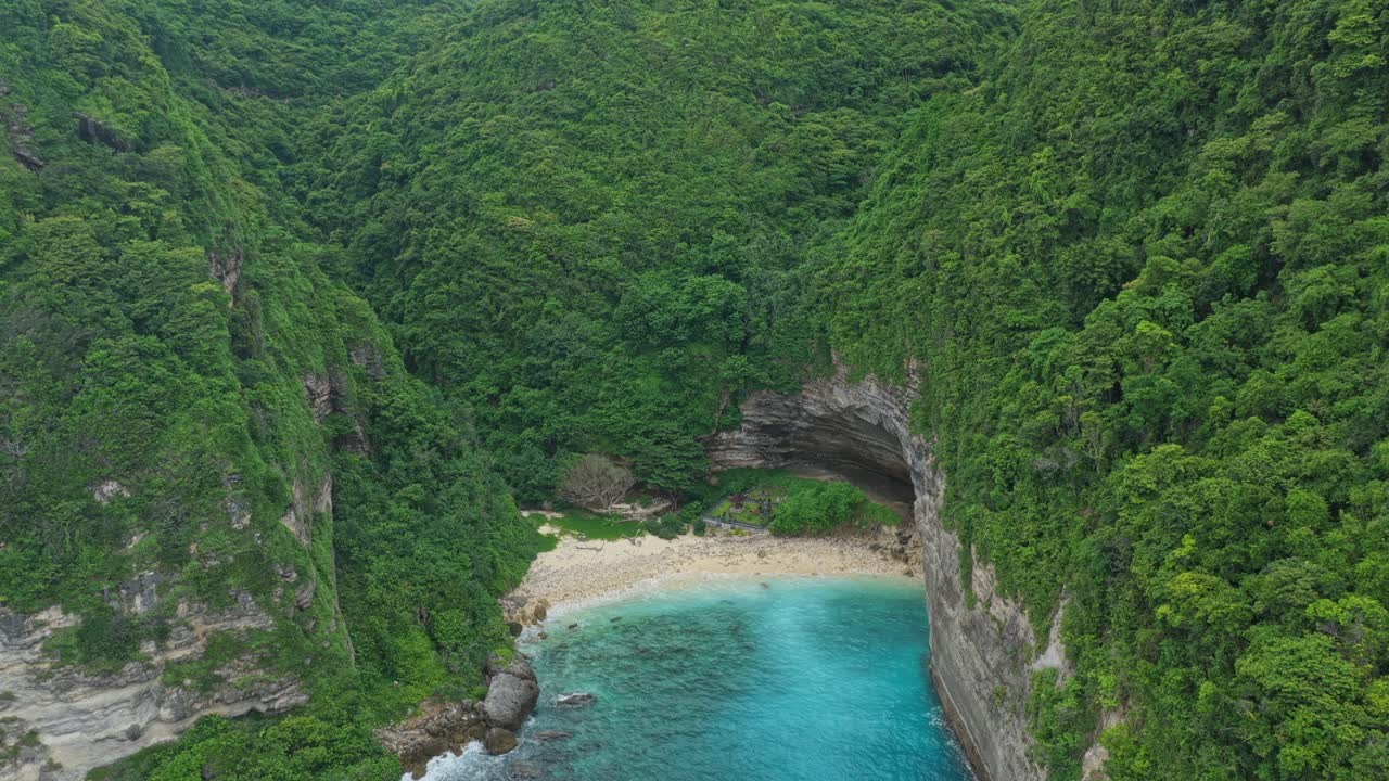 Nusa Penida'da bulunan gizli tropikal plaja doğru uçan drone.
