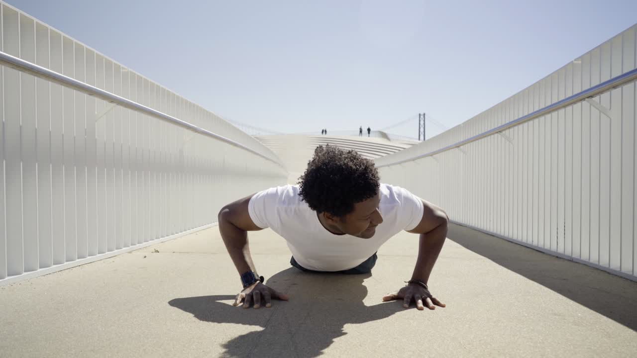 Focused sporty young man doing push-ups on bridge.