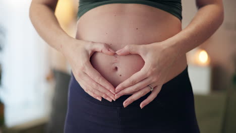 pregnant woman making heart shape on her belly