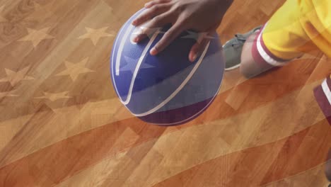 animation of flag of america over african american basketball player dribbling ball in court