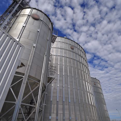 modern granary outdoors. metallic elevators for storing grain. agricultural complex with big aluminum containers under the blue sky.