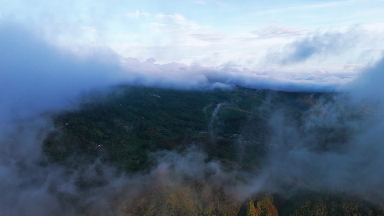Cinematic aerial drone view of mist and clouds covering lush green mountain landscape with soft evening light, ideal for travel, nature, eco projects, documentaries, and inspirational cinematic story