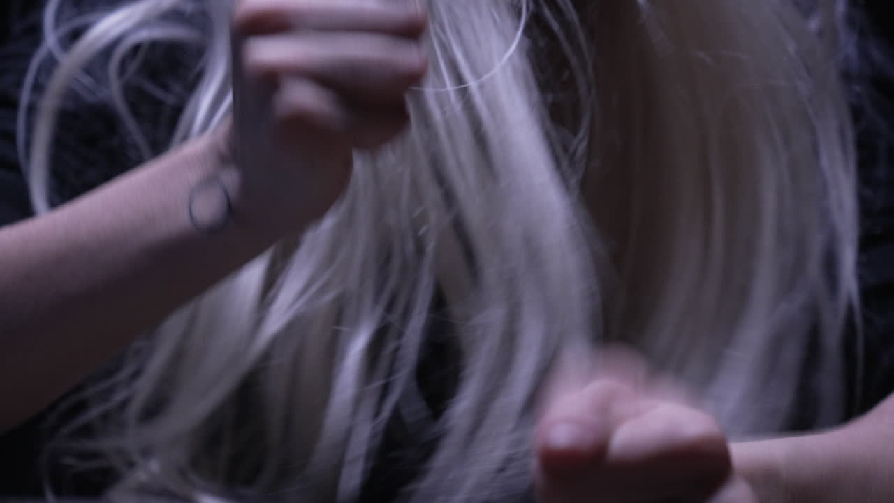 머리 위 조명 하나가 비추는 어두컴컴한 방에서 스트레스로 머리를 흔드는 금발 여성