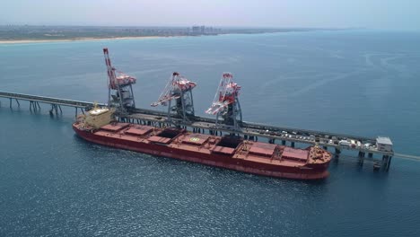 aerial footage of a large bulk carrier offloading coal for a large scale power plant