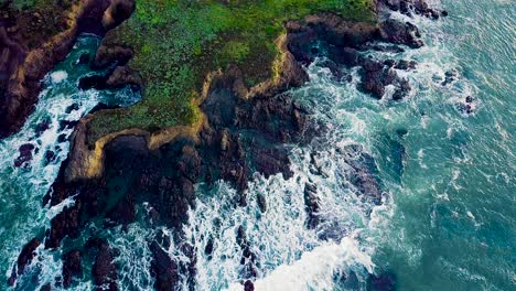 waves crash against jagged rocky cliffs on california coast at sunrise