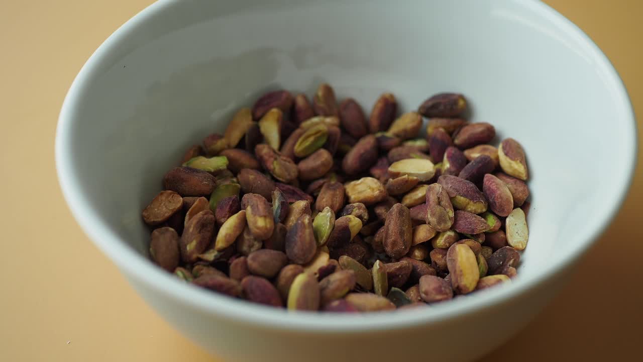 Persona che prende pistacchi da una ciotola