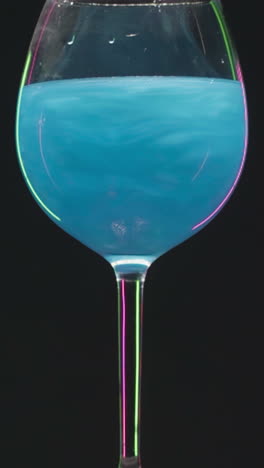 vibrant blue liquid in a wine glass with neon light