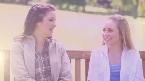 animation of light over happy caucasian teenager girls talking outdoors