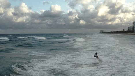 Kiteboarder-riding-along-the-shore-at-various-different-aerial-angles-doing-some-jumps-and-tricks