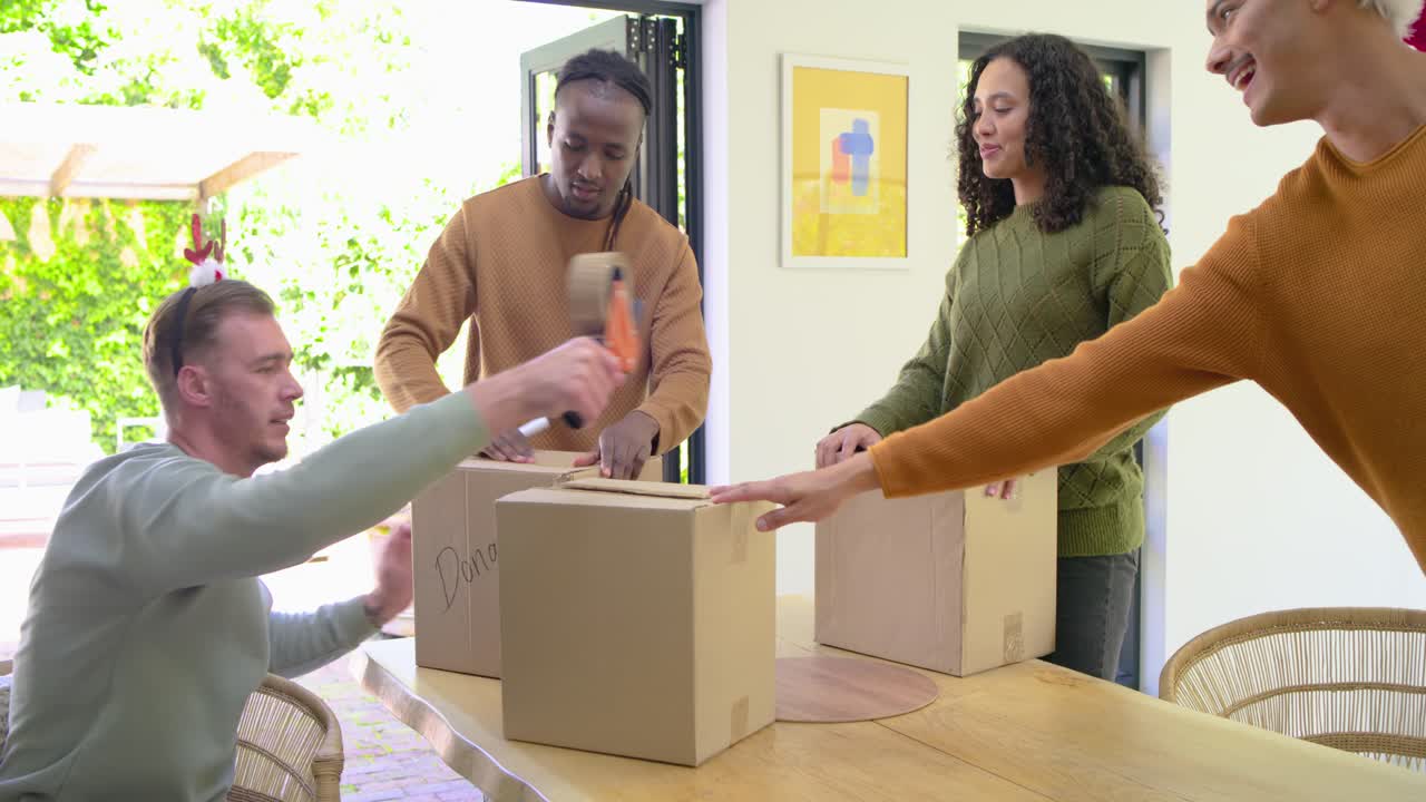 Gathering at home diverse volunteers opening boxes, taping, writing Donation, high-fiving