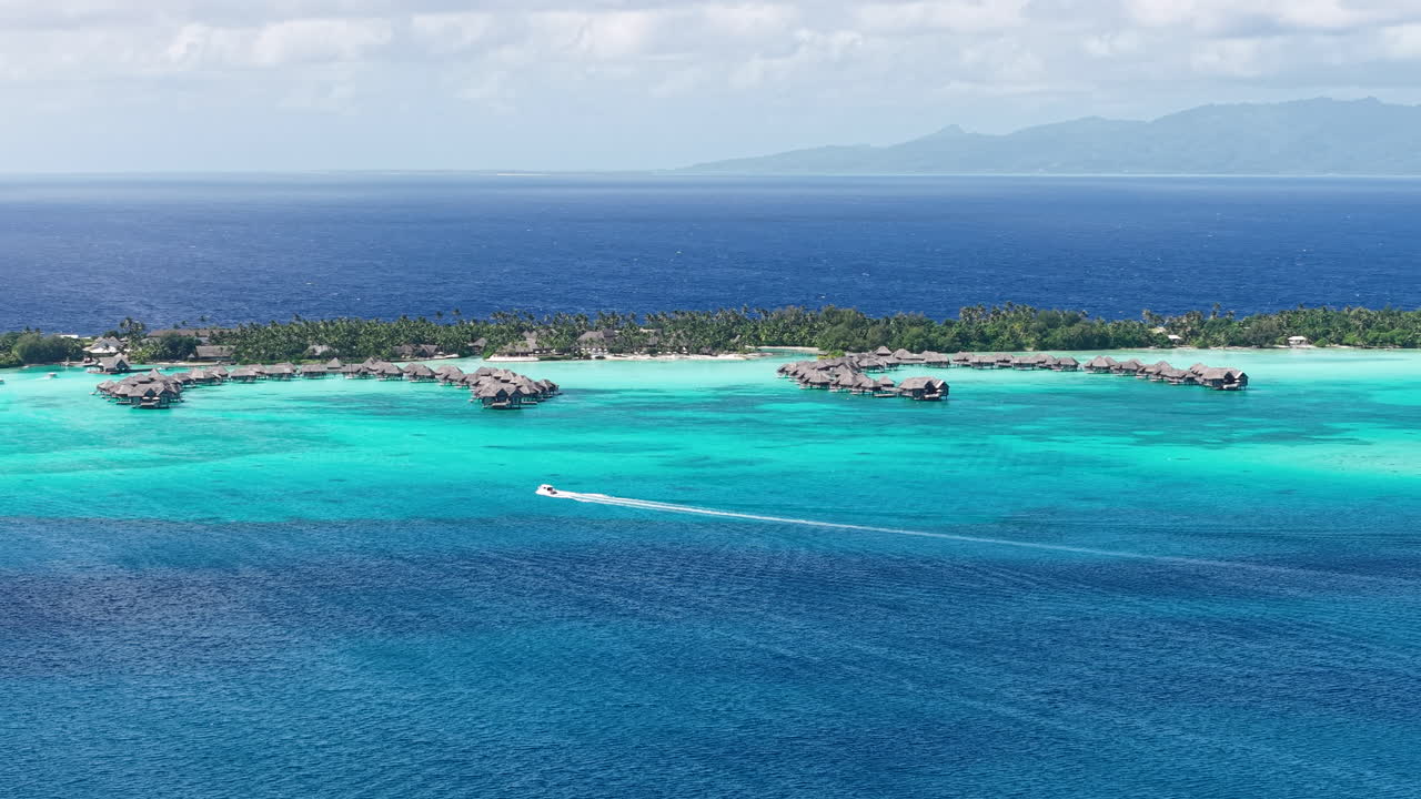 Bora Bora Island, Fransk Polynesien. Dronefoto af båd i turkisblå lagune og luksusresort med vandbungalows