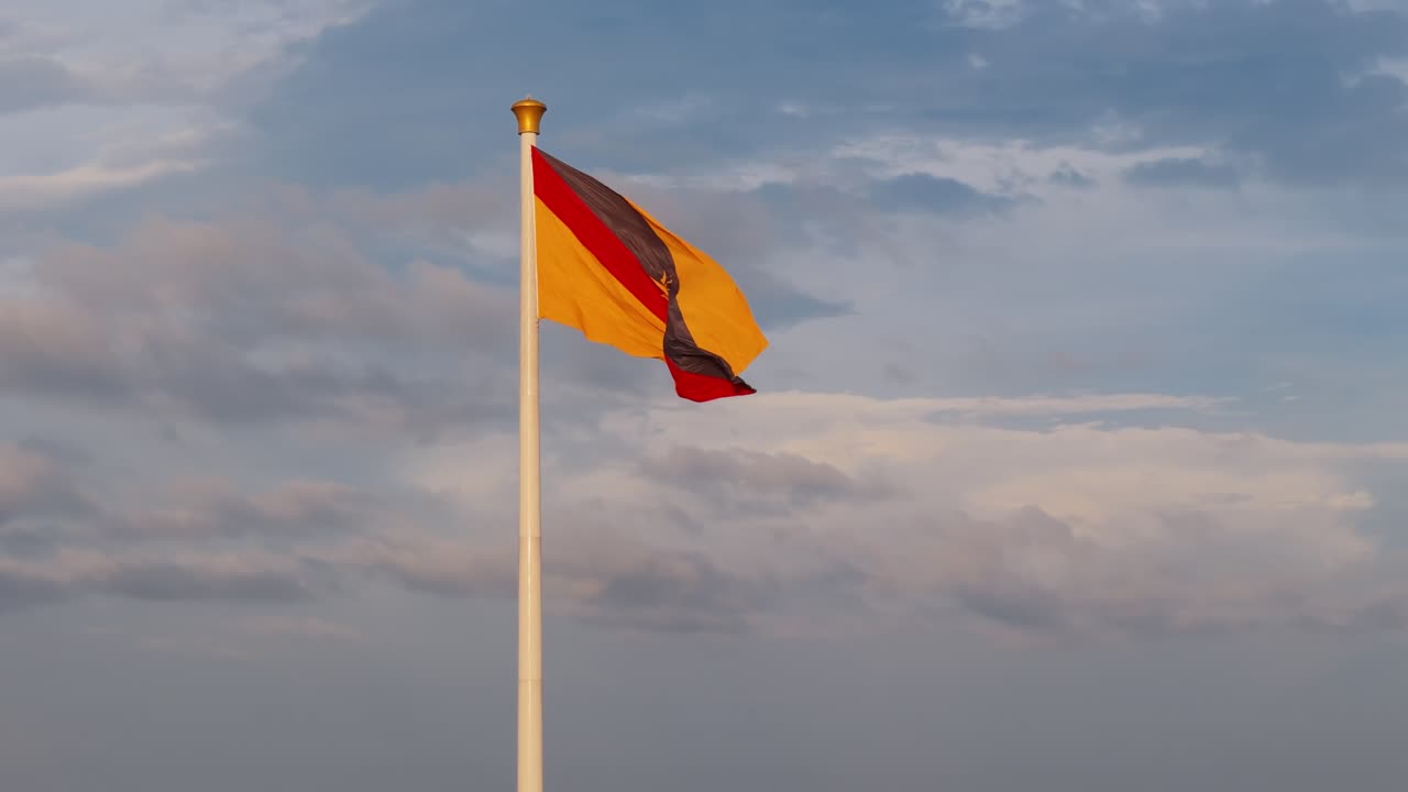 Sarawak state flag fluttering proudly against a backdrop of soft clouds during early evening light.