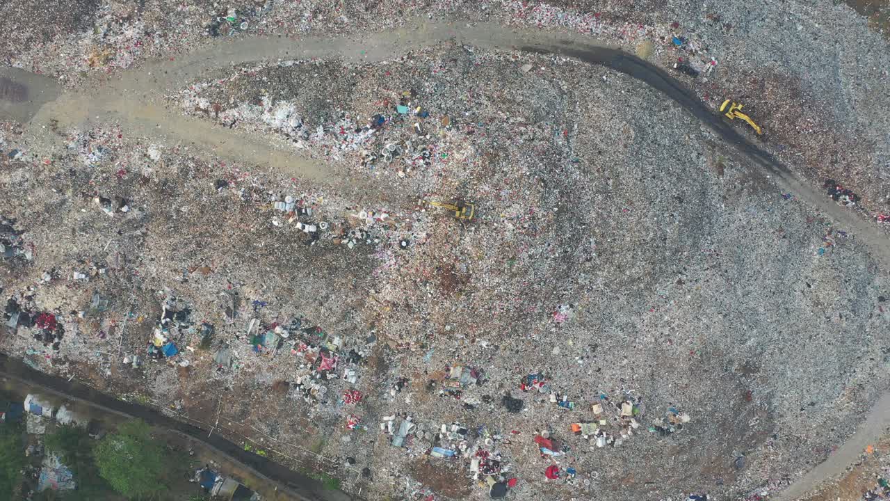 vista aérea de un gran vertedero con materiales de desecho y una excavadora amarilla